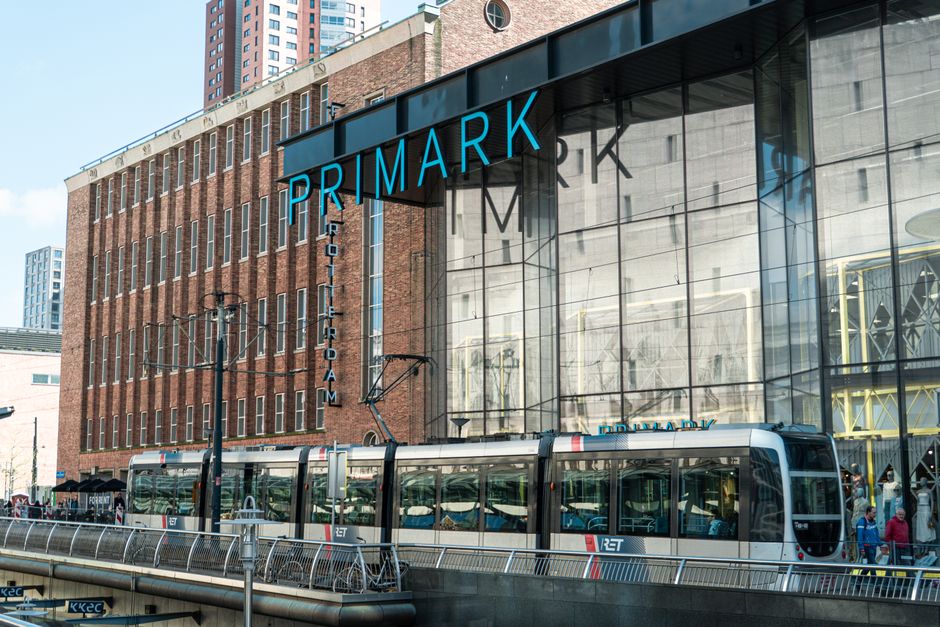 Exterior view of a modern retail space with large glass windows and a prominent blue 